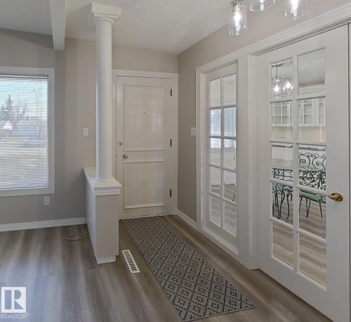 Entryway featuring wood-finish flooring, a decorative column, and a paneled front door - 9624 75 Street, Edmonton, AB - Indoor Photo Showing Other Room