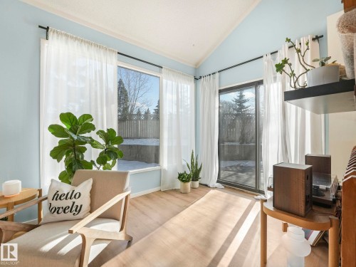This inviting room features vaulted ceilings, light-colored flooring, and large windows with sheer white curtains - 12219 25 Avenue, Edmonton, AB - Indoor