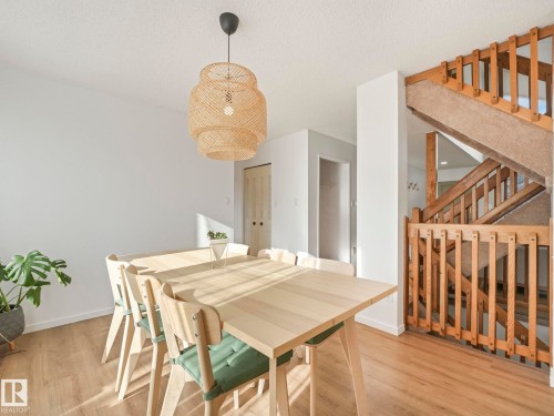 The property features light wood flooring and a wooden staircase with carpeted treads - 12219 25 Avenue, Edmonton, AB - Indoor Photo Showing Dining Room