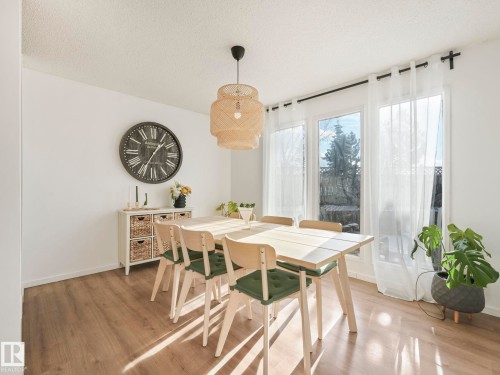 The property features hard flooring, large windows providing abundant natural light, and a stylish woven light fixture - 12219 25 Avenue, Edmonton, AB - Indoor Photo Showing Dining Room