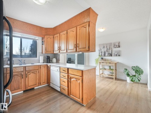 The kitchen features wood cabinetry, white countertops, and a window above the sink - 12219 25 Avenue, Edmonton, AB - Indoor Photo Showing Kitchen