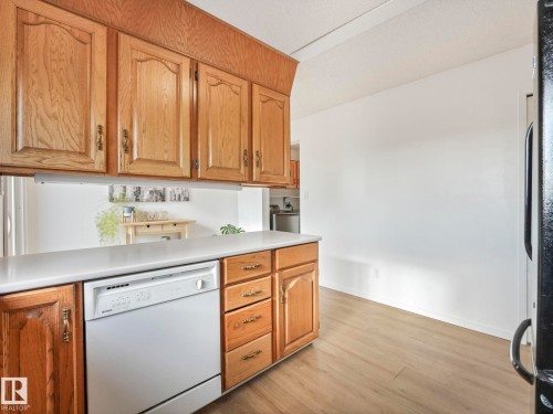 The kitchen features wood cabinetry, a white countertop, and a white dishwasher - 12219 25 Avenue, Edmonton, AB - Indoor Photo Showing Kitchen