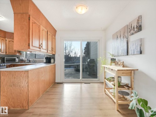 Kitchen area with light wood cabinetry, white countertops, and sliding glass doors leading to the exterior - 12219 25 Avenue, Edmonton, AB - Indoor Photo Showing Kitchen