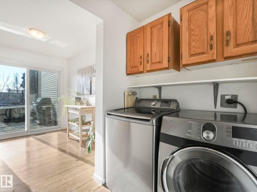 Dedicated laundry area featuring overhead wooden cabinetry and a functional shelf above the appliances - 12219 25 Avenue, Edmonton, AB - Indoor Photo Showing Laundry Room