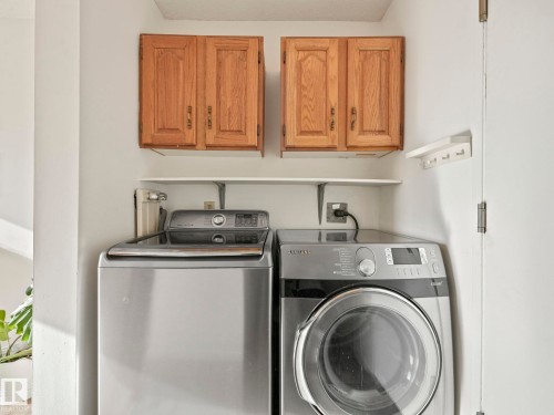 Utility area featuring two wooden cabinets, two white shelves, and a wall-mounted coat rack - 12219 25 Avenue, Edmonton, AB - Indoor Photo Showing Laundry Room