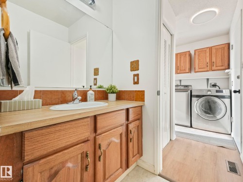 Bathroom vanity with a large mirror, integrated sink, and wood cabinetry - 12219 25 Avenue, Edmonton, AB - Indoor Photo Showing Laundry Room