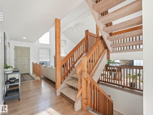 The property features a staircase with light wood banisters and carpeted treads, alongside light wood flooring in the entryway - 12219 25 Avenue, Edmonton, AB - Indoor Photo Showing Other Room
