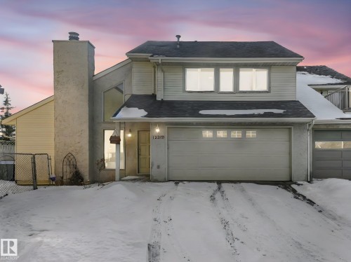 The property features an attached double garage and a single garage, with a prominent chimney on the facade - 12219 25 Avenue, Edmonton, AB - Outdoor