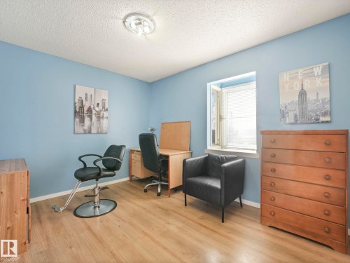 This space features light wood-style flooring, a window with blinds, and light blue walls - 12219 25 Avenue, Edmonton, AB - Indoor