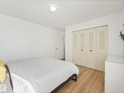 Room featuring light wood-style flooring, a ceiling-mounted light fixture, and bifold closet doors - 12219 25 Avenue, Edmonton, AB - Indoor Photo Showing Bedroom