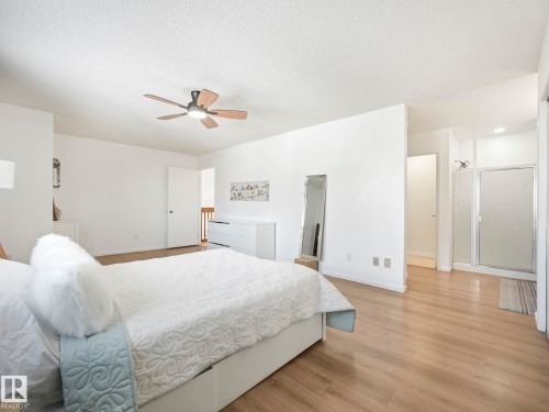 This sleeping area features light wood-style flooring, a ceiling fan with light, and white walls - 12219 25 Avenue, Edmonton, AB - Indoor Photo Showing Bedroom