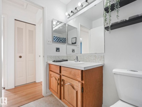 The bathroom features a light wood vanity with a white countertop and a mirror with overhead lighting - 12219 25 Avenue, Edmonton, AB - Indoor Photo Showing Bathroom