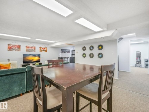 The property features a spacious room with carpeted flooring, recessed lighting, and ample space for various activities - 12219 25 Avenue, Edmonton, AB - Indoor