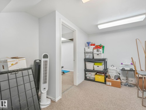The property features a room with light-colored walls and carpeted flooring, providing a versatile space - 12219 25 Avenue, Edmonton, AB - Indoor