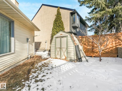 The property includes a shed and a wooden fence, with mature trees providing natural screening - 12219 25 Avenue, Edmonton, AB - Outdoor With Exterior