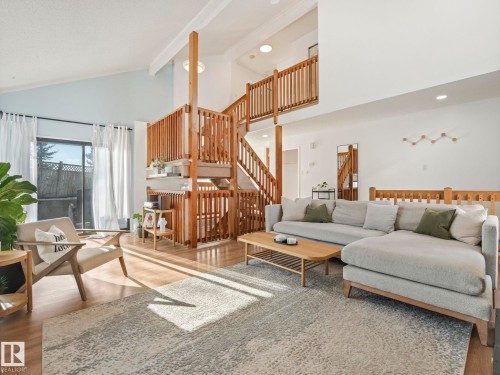 Spacious living area featuring high vaulted ceilings, light wood flooring, and a multi-level wooden staircase with railings - 12219 25 Avenue, Edmonton, AB - Indoor Photo Showing Living Room