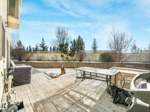 The property features a spacious wooden deck, with a retaining wall and fenced perimeter - 12219 25 Avenue, Edmonton, AB - Outdoor With Deck Patio Veranda