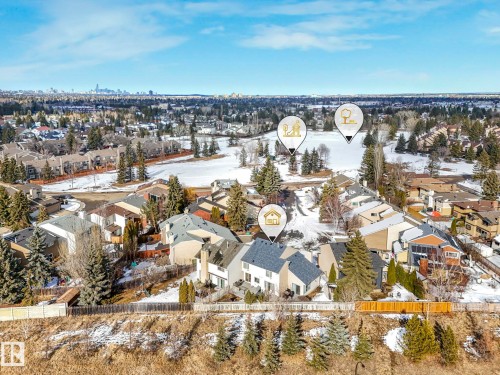Aerial view showcasing the property within a residential area, featuring a distant city skyline, mature trees, and snow-covered ground - 12219 25 Avenue, Edmonton, AB - Outdoor With View
