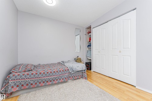 This room features light grey walls, a white bi-fold closet, and light wood flooring - 10412 39 Avenue, Edmonton, AB - Indoor Photo Showing Bedroom