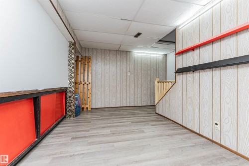 The property features light-colored wood paneling, wood-look flooring, and a white drop ceiling - 10412 39 Avenue, Edmonton, AB - Indoor Photo Showing Other Room