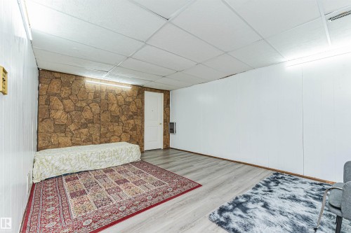 This room features wood plank flooring, white panel walls, and a stone-look accent wall - 10412 39 Avenue, Edmonton, AB - Indoor Photo Showing Other Room