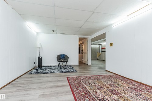 Interior space featuring light-toned flooring, white paneled walls, and a drop ceiling - 10412 39 Avenue, Edmonton, AB - Indoor