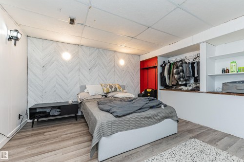This room features a decorative accent wall with a chevron pattern, a built-in wardrobe with hanging space, and shelving - 10412 39 Avenue, Edmonton, AB - Indoor Photo Showing Bedroom