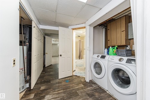 The property features a dedicated laundry area with a washer and dryer, along with wood-look flooring and white paneled doors - 10412 39 Avenue, Edmonton, AB - Indoor Photo Showing Laundry Room