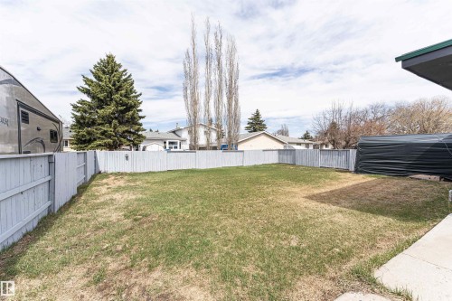 Expansive backyard featuring a partial concrete patio, mature evergreen tree, and full perimeter fencing - 10412 39 Avenue, Edmonton, AB - Outdoor