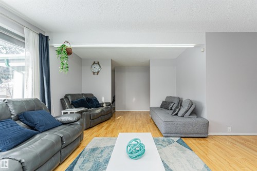 Living area with hardwood floors, light gray walls, and large windows - 10412 39 Avenue, Edmonton, AB - Indoor Photo Showing Living Room