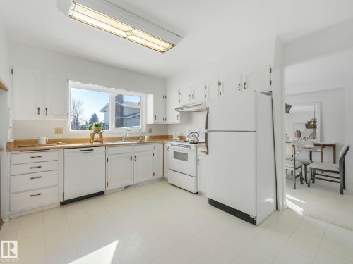 The kitchen features white cabinetry, light-colored countertops, and white appliances including a refrigerator, oven, and dishwasher - 3421 112A Street, Edmonton, AB - Indoor Photo Showing Kitchen