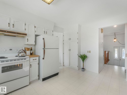 The kitchen features white cabinetry, a white refrigerator, and a white electric range - 3421 112A Street, Edmonton, AB - Indoor Photo Showing Kitchen