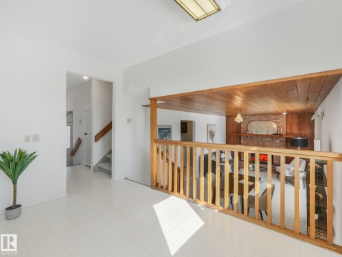 Living area featuring a wooden railing and a view of the fireplace - 3421 112A Street, Edmonton, AB - Indoor Photo Showing Other Room