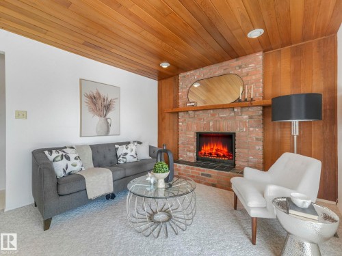 Living space featuring a brick fireplace, wood paneling, and a wood plank ceiling - 3421 112A Street, Edmonton, AB - Indoor Photo Showing Living Room With Fireplace