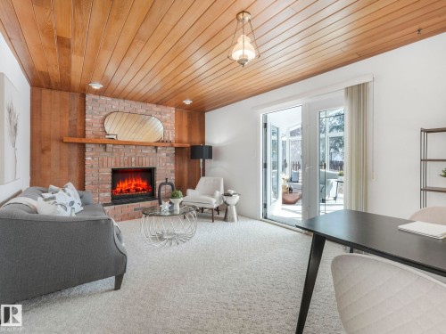 This living area features a brick fireplace with a wood mantle, wood paneling, and a wood plank ceiling - 3421 112A Street, Edmonton, AB - Indoor Photo Showing Living Room With Fireplace