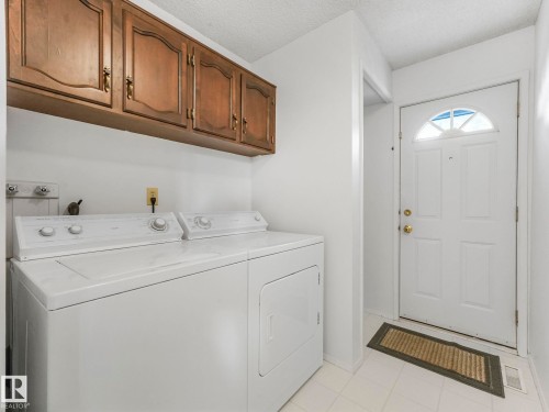 A functional laundry area featuring overhead wooden cabinetry for storage - 3421 112A Street, Edmonton, AB - Indoor Photo Showing Laundry Room