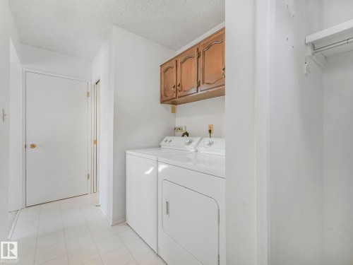 Dedicated laundry area featuring a washer and dryer, wood cabinetry, and a storage closet with a hanging rod - 3421 112A Street, Edmonton, AB - Indoor Photo Showing Laundry Room