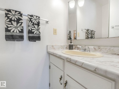 Bathroom vanity featuring a light-colored countertop, an oval sink, and a mirrored cabinet above - 3421 112A Street, Edmonton, AB - Indoor Photo Showing Bathroom