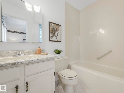 Bathroom featuring a white vanity with a marble-style countertop, a built-in sink, and a mirrored medicine cabinet with integrated lighting - 3421 112A Street, Edmonton, AB - Indoor Photo Showing Bathroom