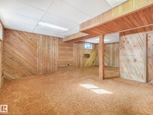 This room features wood paneling on the walls, a drop ceiling with recessed lighting, and a window providing natural light - 3421 112A Street, Edmonton, AB - Indoor Photo Showing Basement