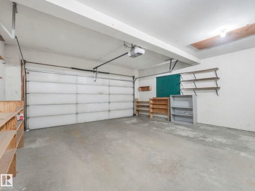 The garage features a concrete floor, a white overhead door, and overhead lighting - 3421 112A Street, Edmonton, AB - Indoor Photo Showing Garage