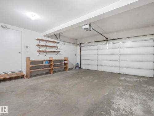 The property features an attached garage with a concrete floor, a garage door, and a built-in shelving unit - 3421 112A Street, Edmonton, AB - Indoor Photo Showing Garage
