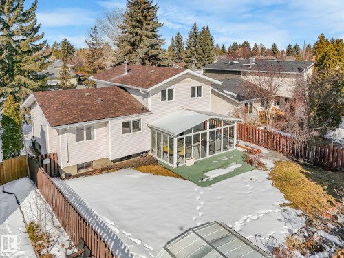 This property features a sunroom with large windows, a fenced yard, and an additional outbuilding with a transparent roof - 3421 112A Street, Edmonton, AB - Outdoor