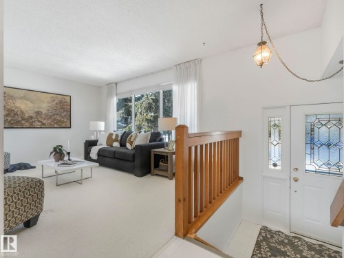 Bright living area featuring extensive windows providing natural light, a white carpet, and a wooden banister - 3421 112A Street, Edmonton, AB - Indoor