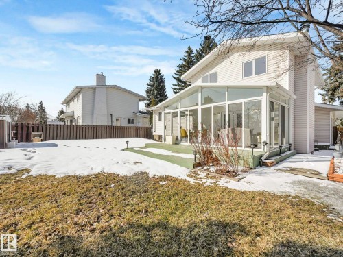 The property features a sunroom with large windows, a side yard with a fence, and an exterior with horizontal siding - 3421 112A Street, Edmonton, AB - Outdoor