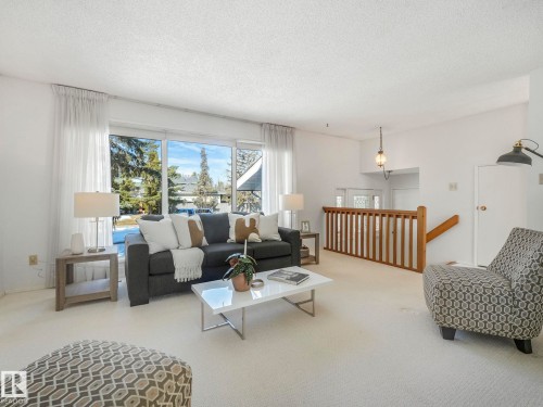 Living area featuring large windows providing natural light, a neutral color palette, and carpeted floors - 3421 112A Street, Edmonton, AB - Indoor Photo Showing Living Room