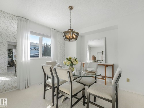 Dining area featuring a glass-top table, six chairs, and a decorative light fixture - 3421 112A Street, Edmonton, AB - Indoor Photo Showing Dining Room