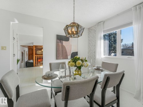 The dining area features a glass-top table with light-colored chairs, illuminated by an overhead decorative chandelier - 3421 112A Street, Edmonton, AB - Indoor Photo Showing Dining Room
