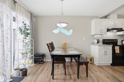 Dining area and kitchen with wood flooring, white cabinetry, and a sliding glass door - 13905 138 St, Edmonton, AB - Indoor