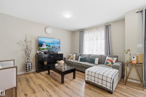 Living area featuring light wood-style flooring, light-colored walls, and a window with sheer and solid curtains - 13905 138 St, Edmonton, AB - Indoor Photo Showing Living Room